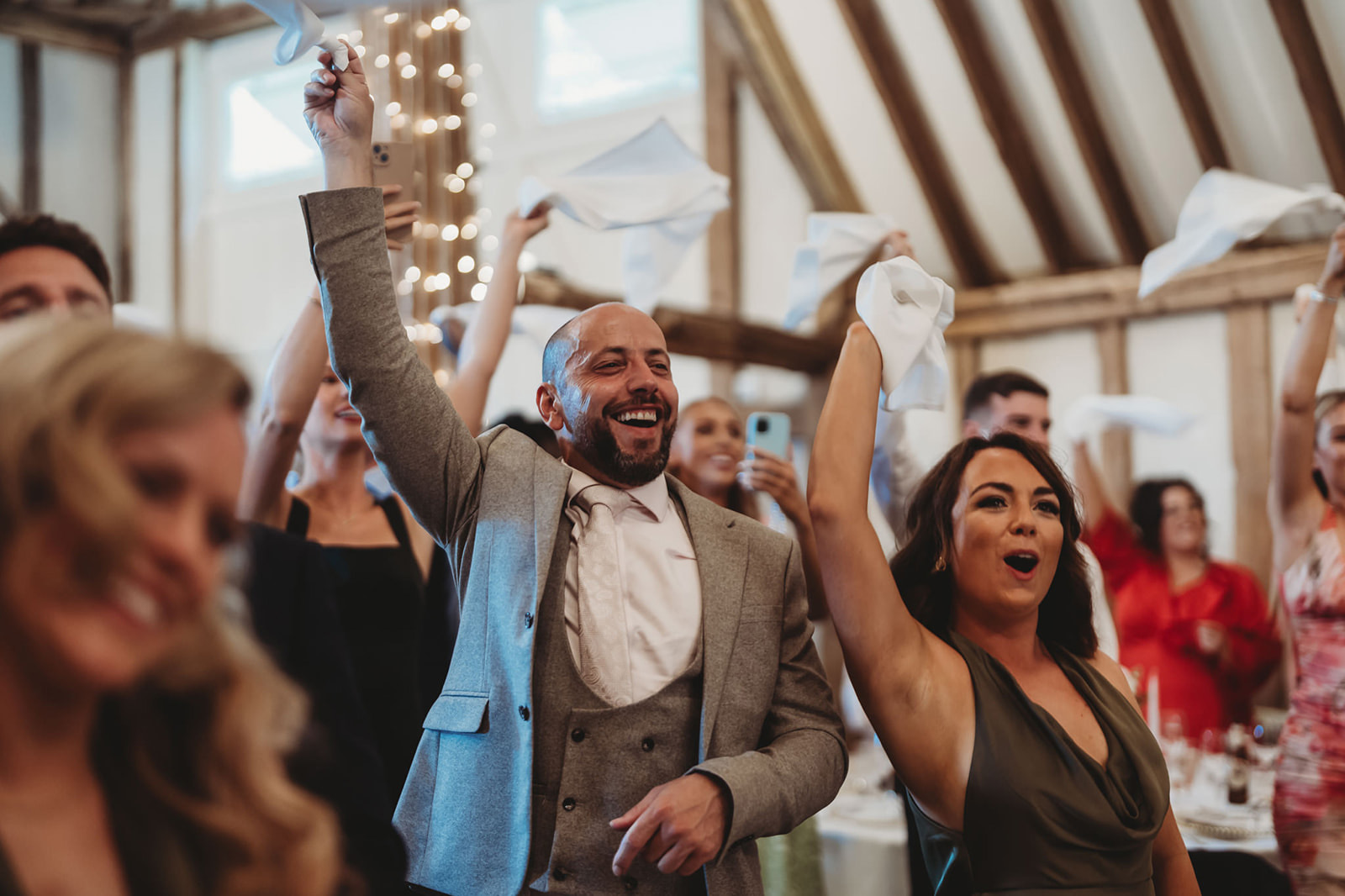 Wedding guests waving napkins above their heads, unposed group photograph