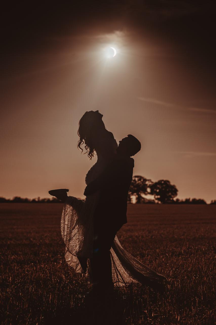 wedding photography — couple silhouette lift beneath the evening sun