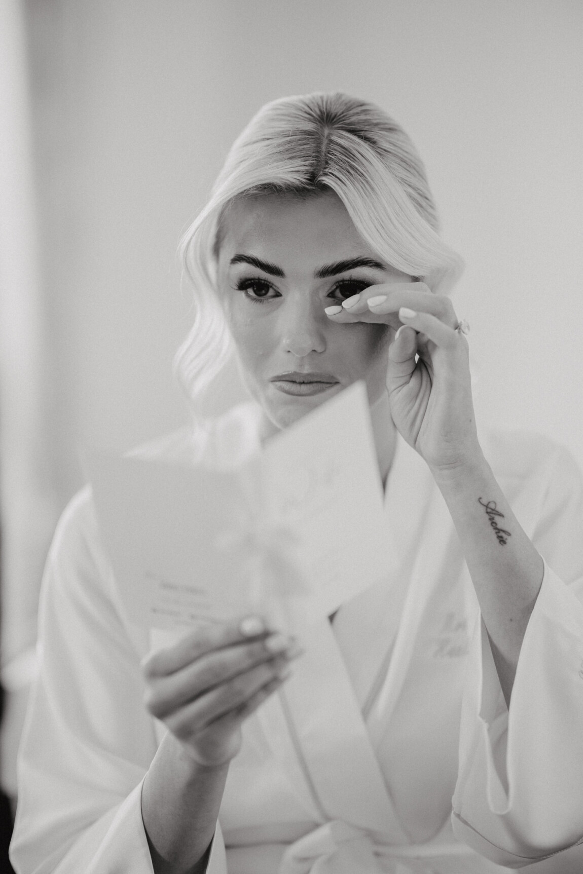 Black and white of a bride crying as she reads a card, documentary wedding photography by Matt Wing