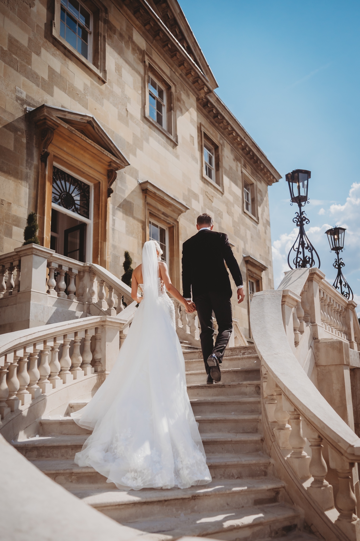 Bride and groom on the sweeping stairs of Botleys Mansion, Surrey