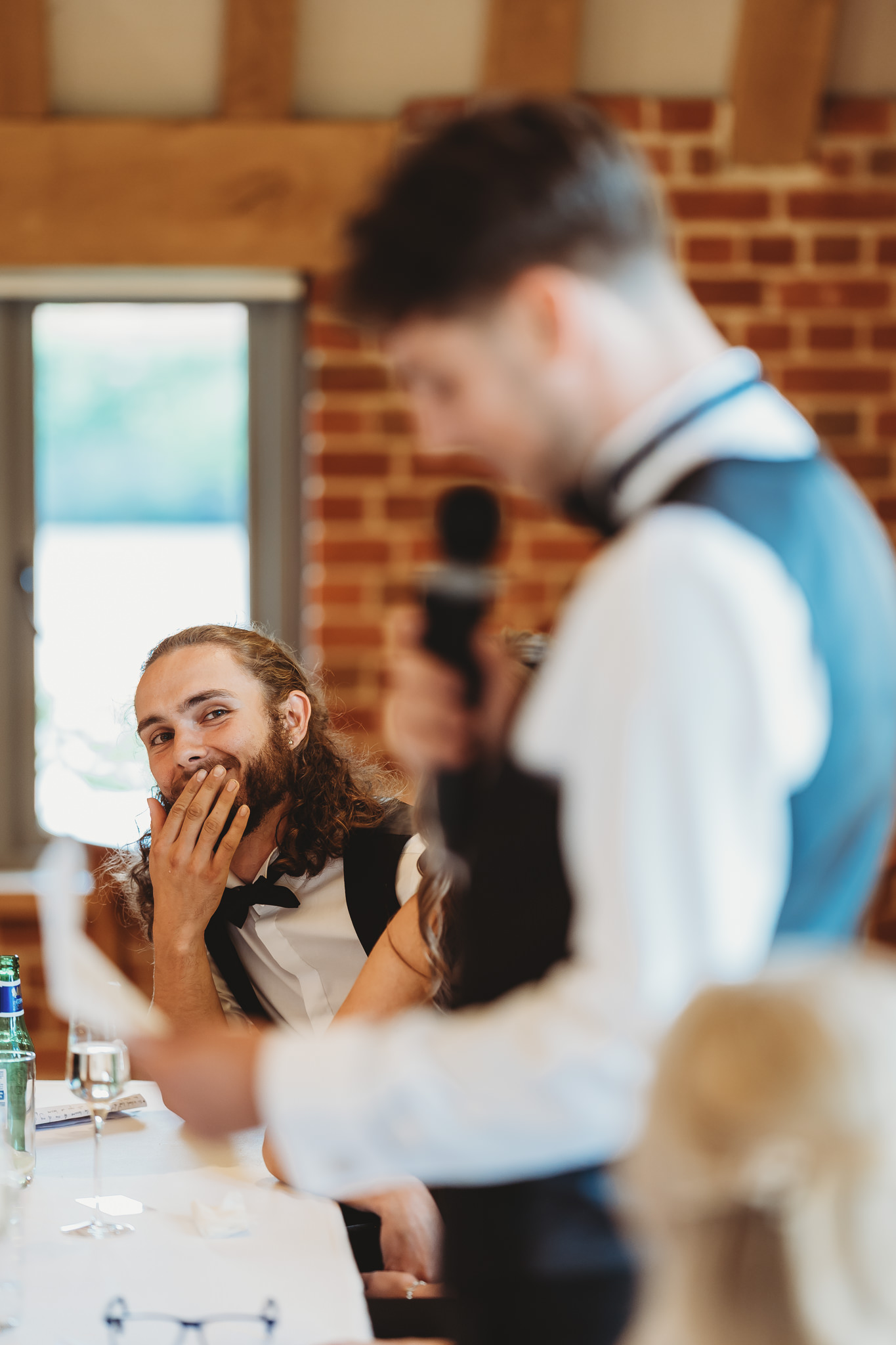 A wedding guest with her hand over her mouth reacting during a speech