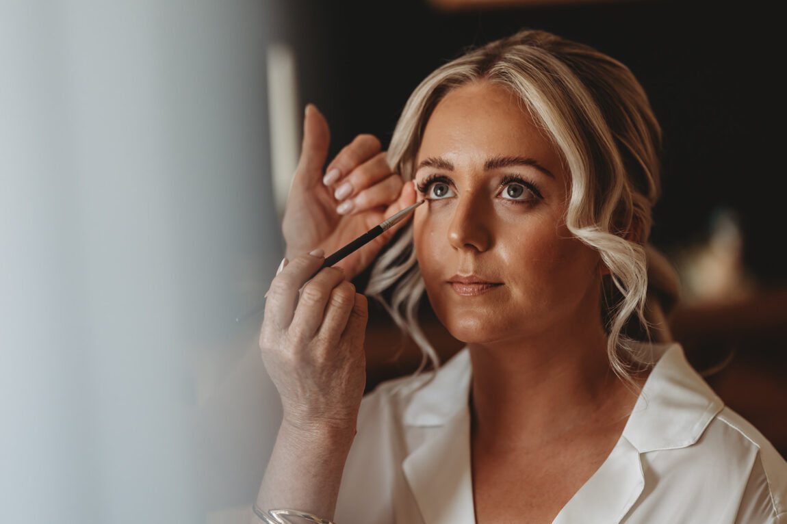 Bride having her make-up finished on the wedding morning