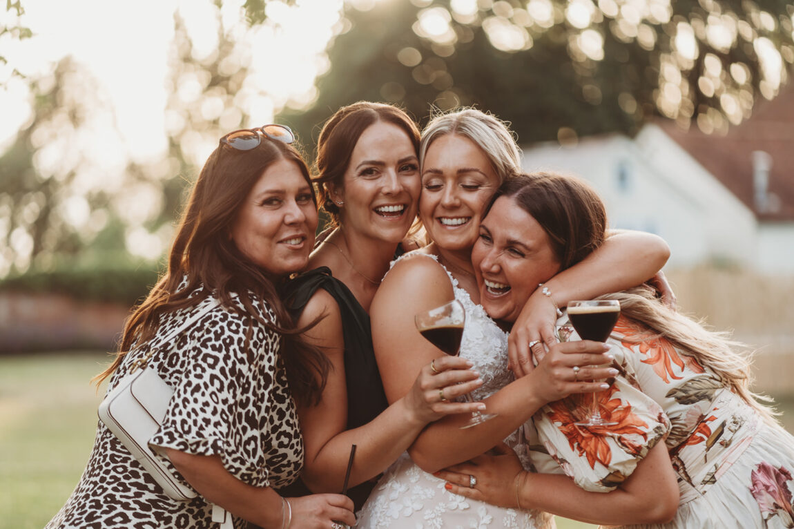 Bride hugging her friends on the lawn in the evening
