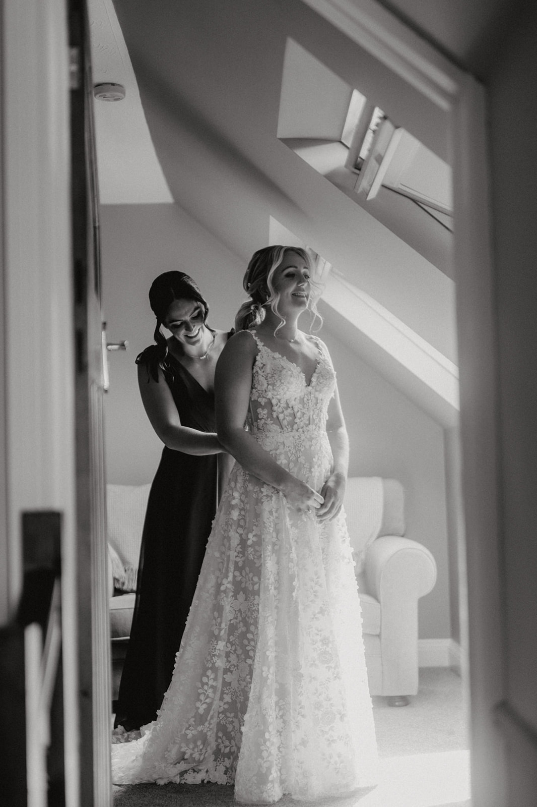 Black and white of the bride being helped into her dress