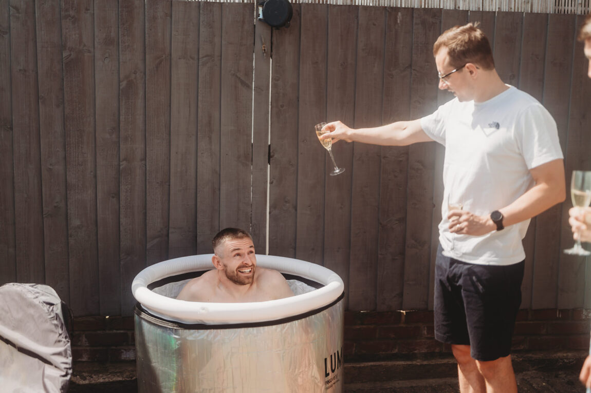 Groom in an ice bath on the wedding morning while his best man pours in more ice
