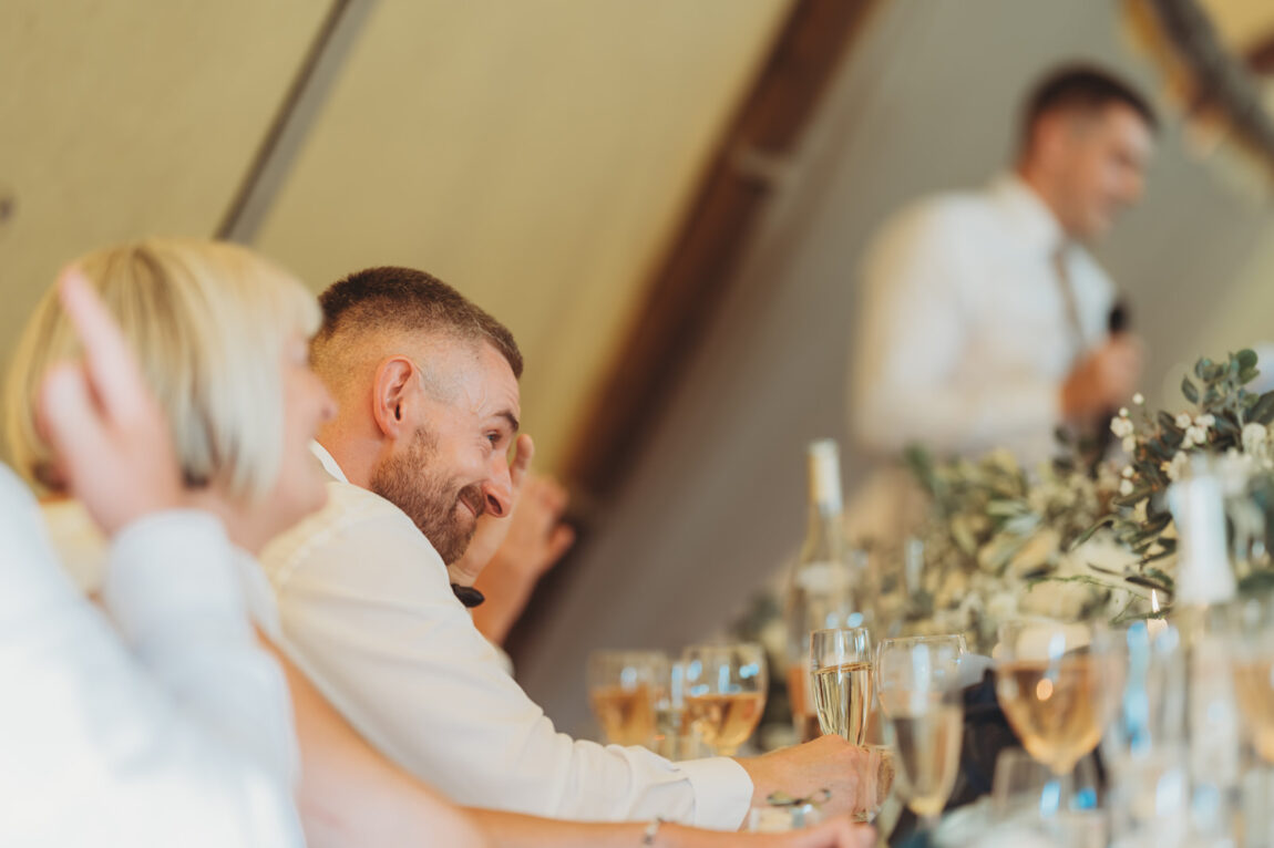 Bride and groom laughing at the speeches in the tipi