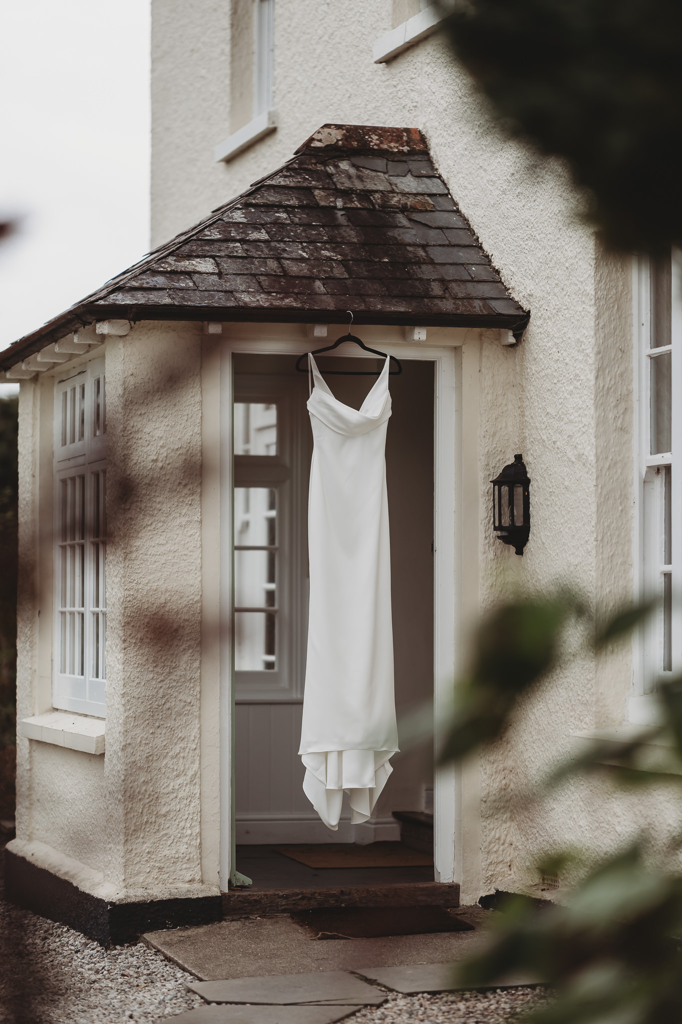 Laura & Liam / The Green Cornwall 3 Laura’s wedding dress hanging in a cottage doorway at The Green Cornwall