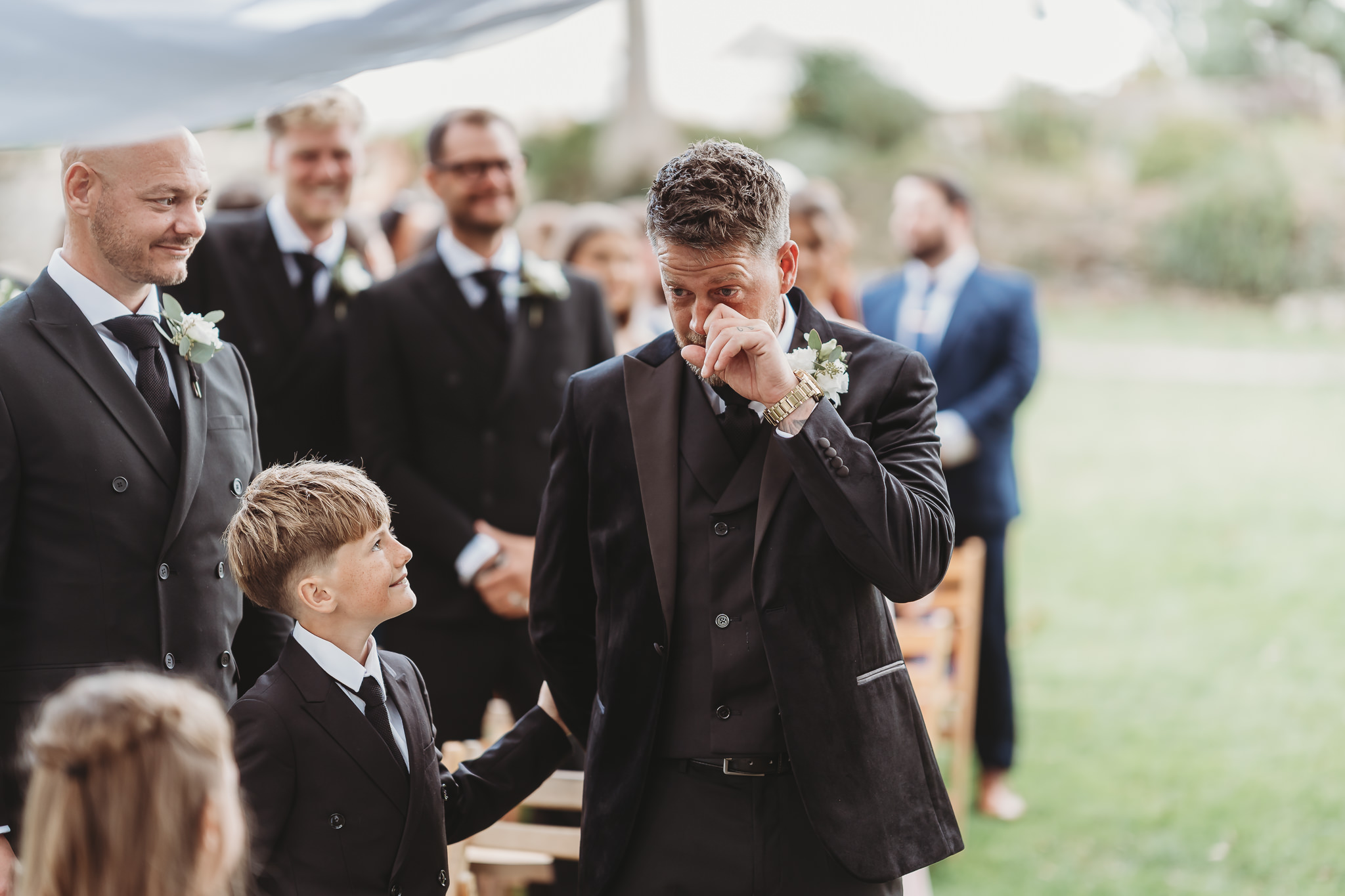 Laura & Liam / The Green Cornwall 14 Liam wiping his eye as the ceremony begins, with his groomsmen beside him