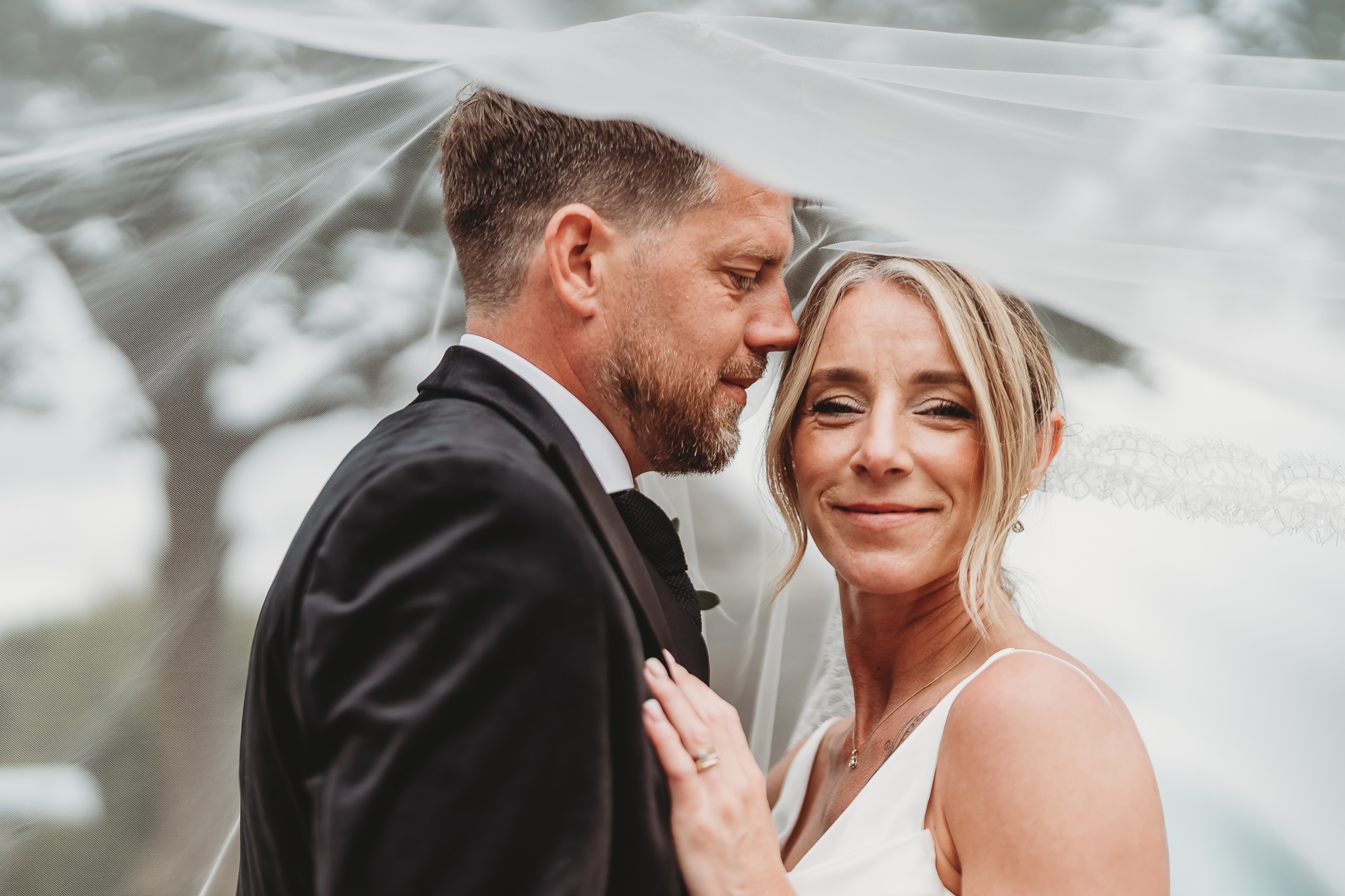 A couple photographed at The Green Cornwall with a veil catching the wind