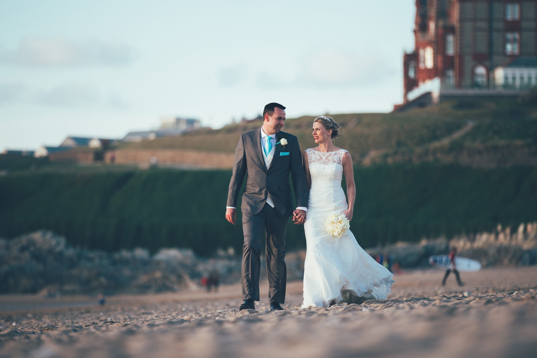 Headland Hotel wedding photographer Matt Wing: bride and groom walking on Fistral Beach below the Headland Hotel