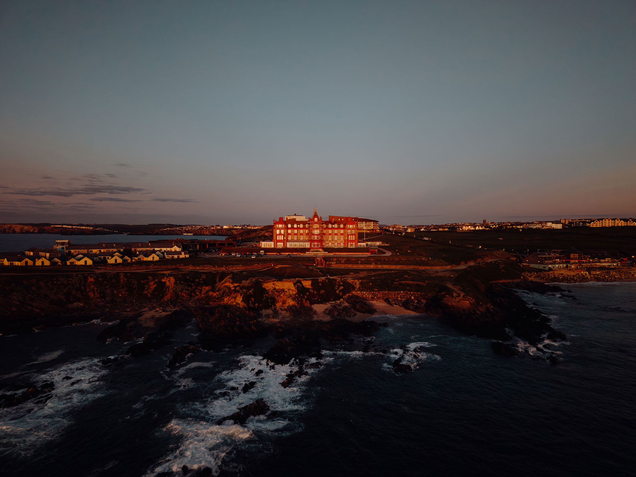 The Headland Hotel on the headland above Fistral Beach, Newquay, lit by the last sun, drone photograph by Headland Hotel wedding photographer Matt Wing