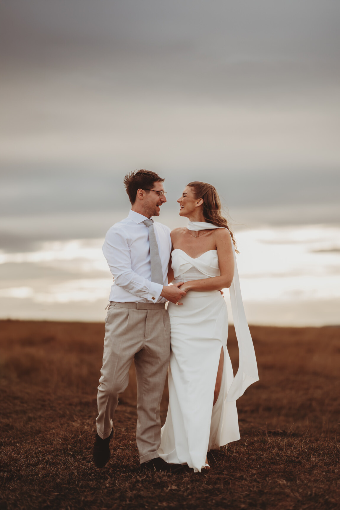 Bride and groom holding each other on an open hillside, documentary wedding photography by Matt Wing