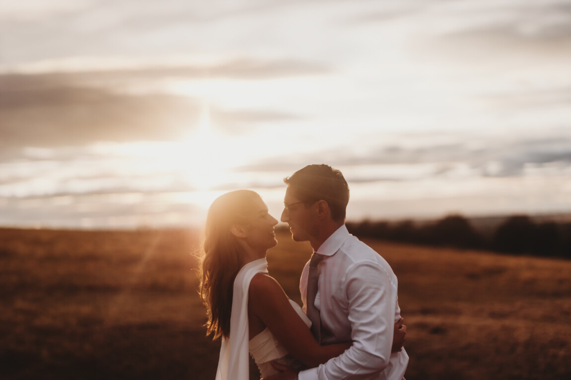 Couple kissing at sunset in an open field, documentary wedding photography by Matt Wing