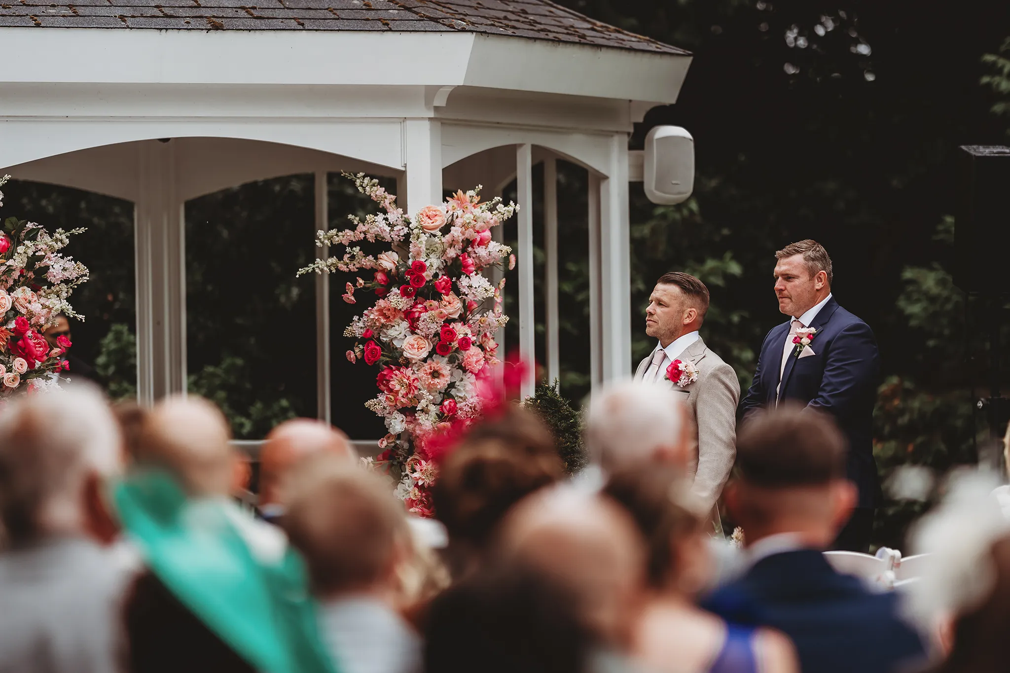 Emily & Alan / The Orangery 19 Vows under the pink and red floral arch by Floral Explosion