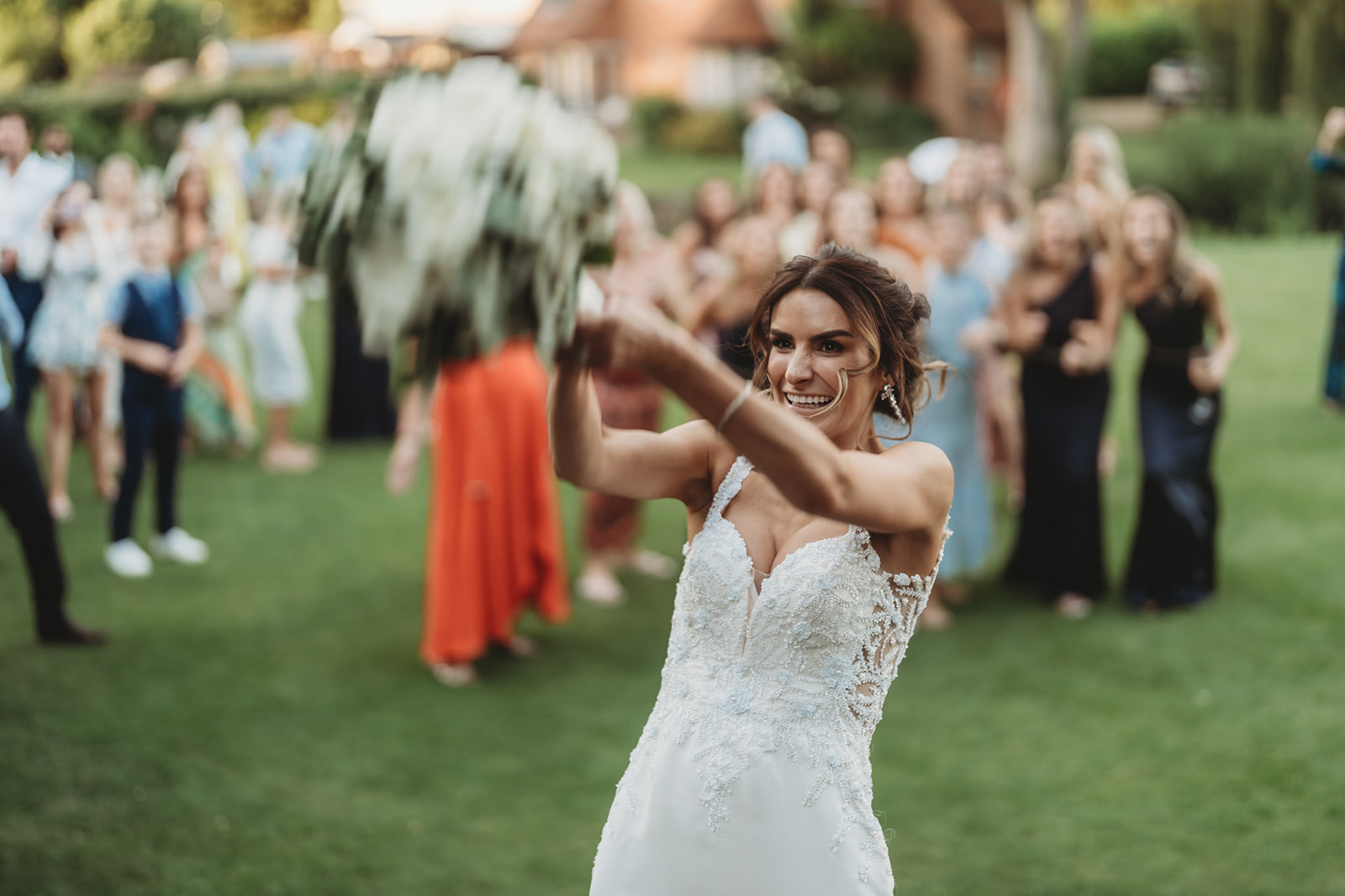 Bride about to throw the bouquet on the lawn at Le Talbooth