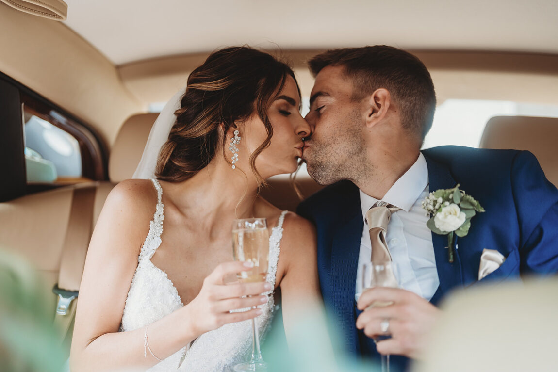 Bride and groom kissing in the back of the wedding car