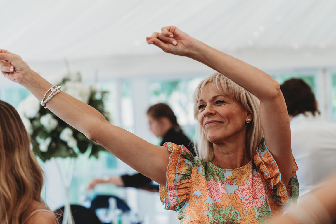 Guest dancing with arms in the air in the marquee at Le Talbooth