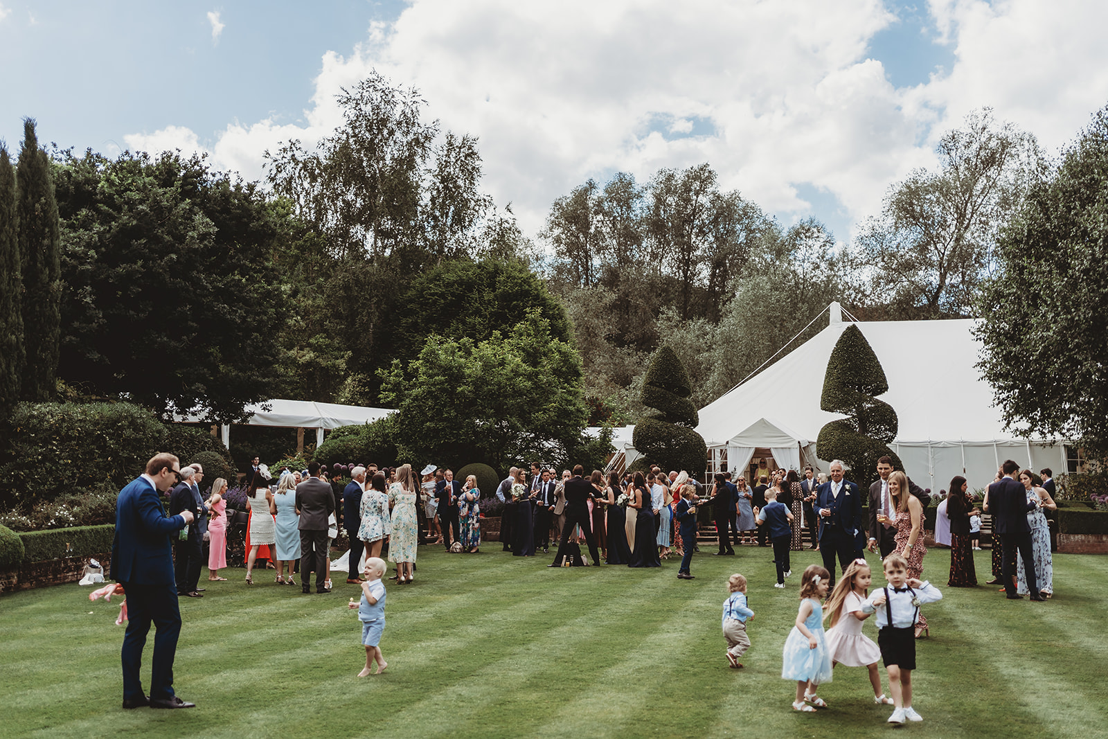 Wedding guests on the lawn in front of the marquee at Le Talbooth