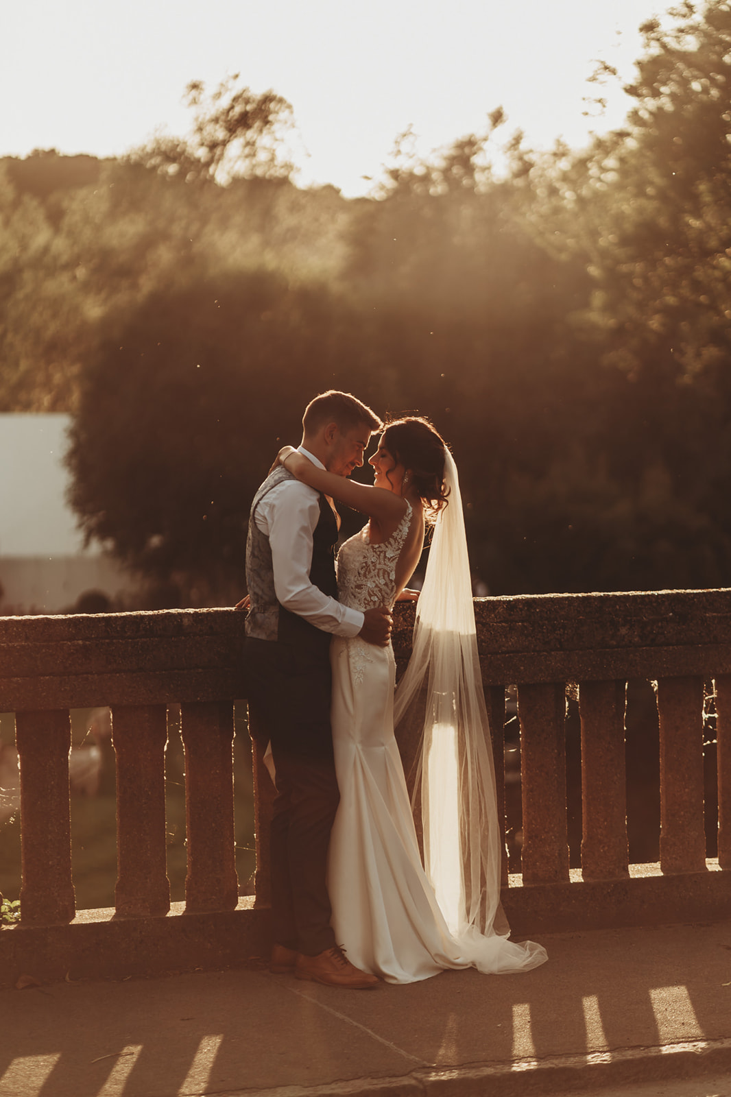 Couple embracing on the stone balustrade at sunset near Le Talbooth