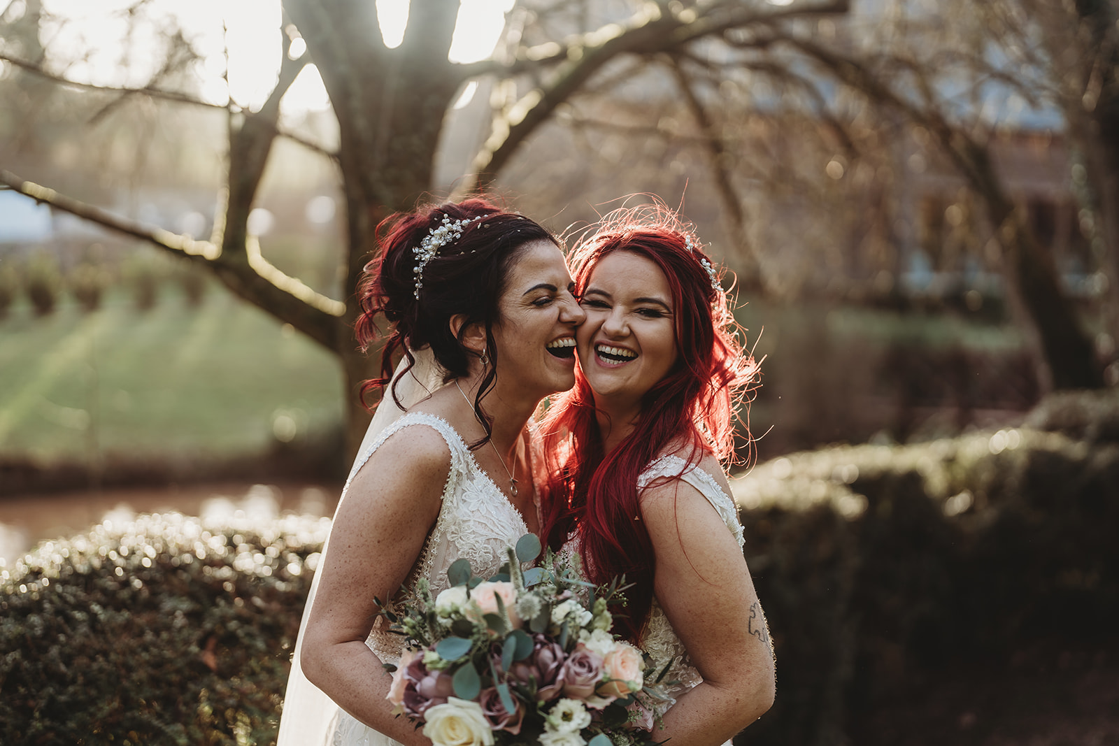 Two brides in low winter sunlight in the gardens at The Mill Barns, by Mill Barns wedding photographer Matt Wing
