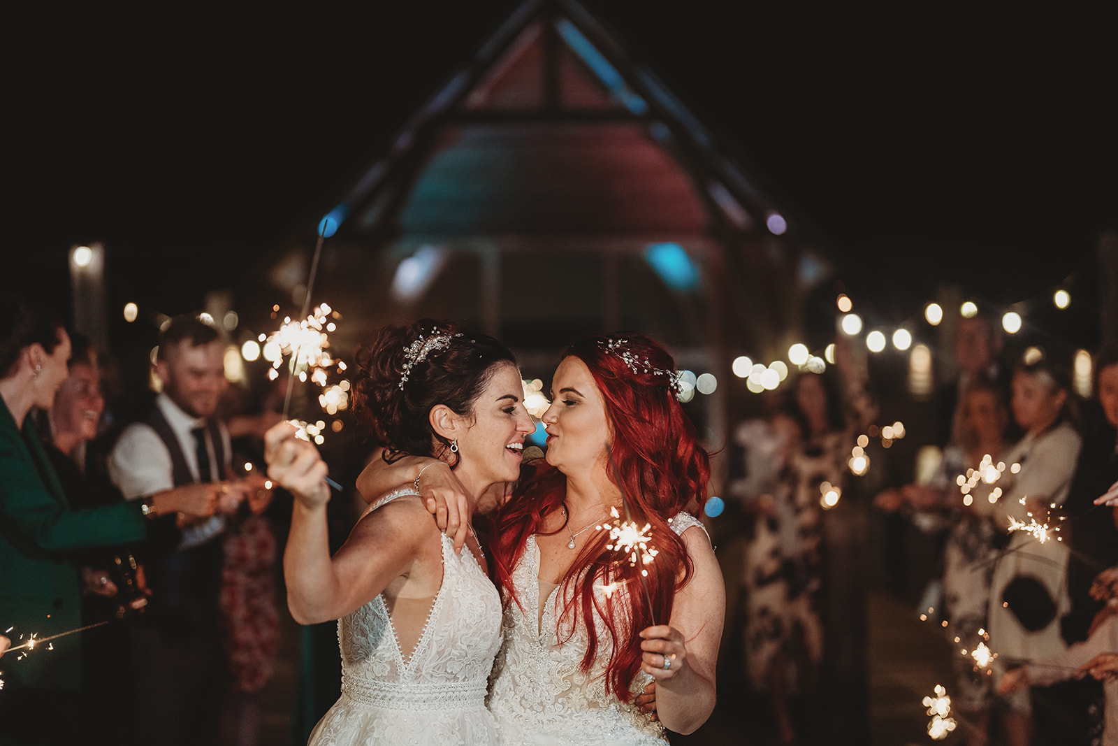 Two brides laughing among sparklers at night at The Mill Barns, Shropshire