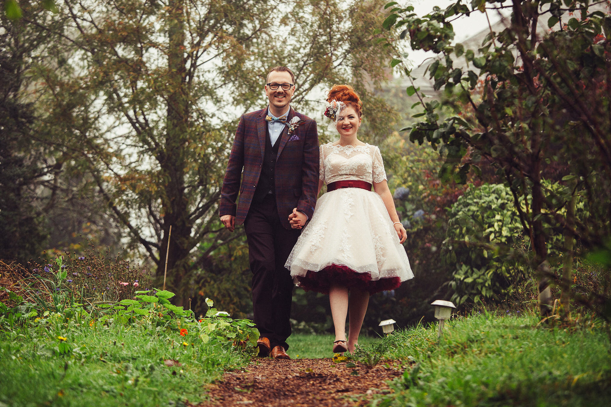 Bride and groom walking through the woodland at Nancarrow Farm