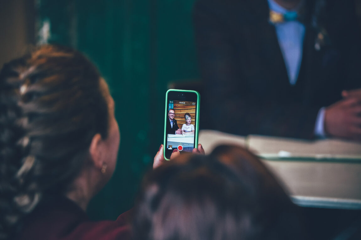 Guest taking a photo on a phone during the ceremony at Nancarrow Farm