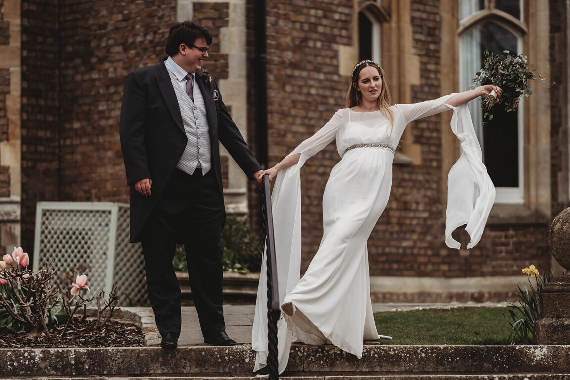 Bride and groom laughing on the steps of Oakley Court