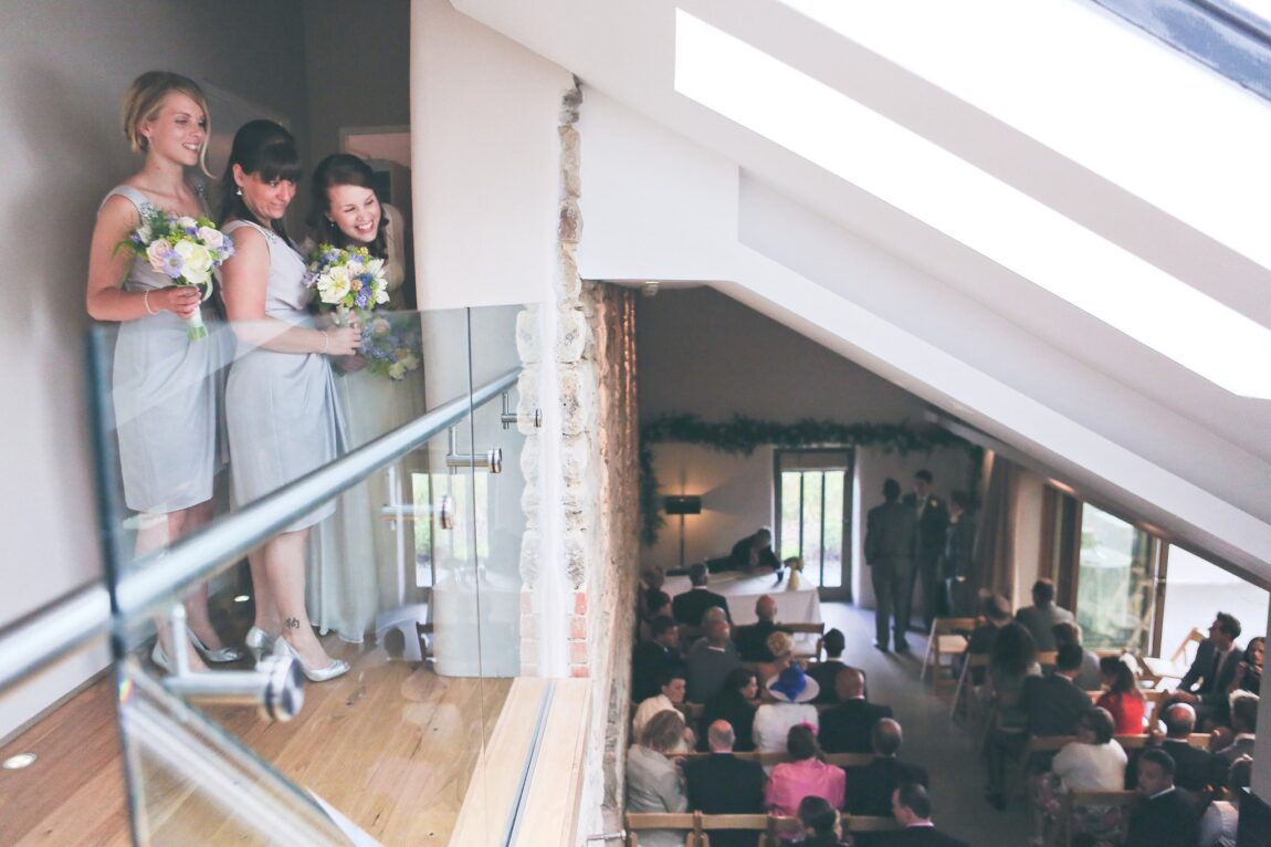 Bridesmaids watching from the balcony above the ceremony room at Trevenna
