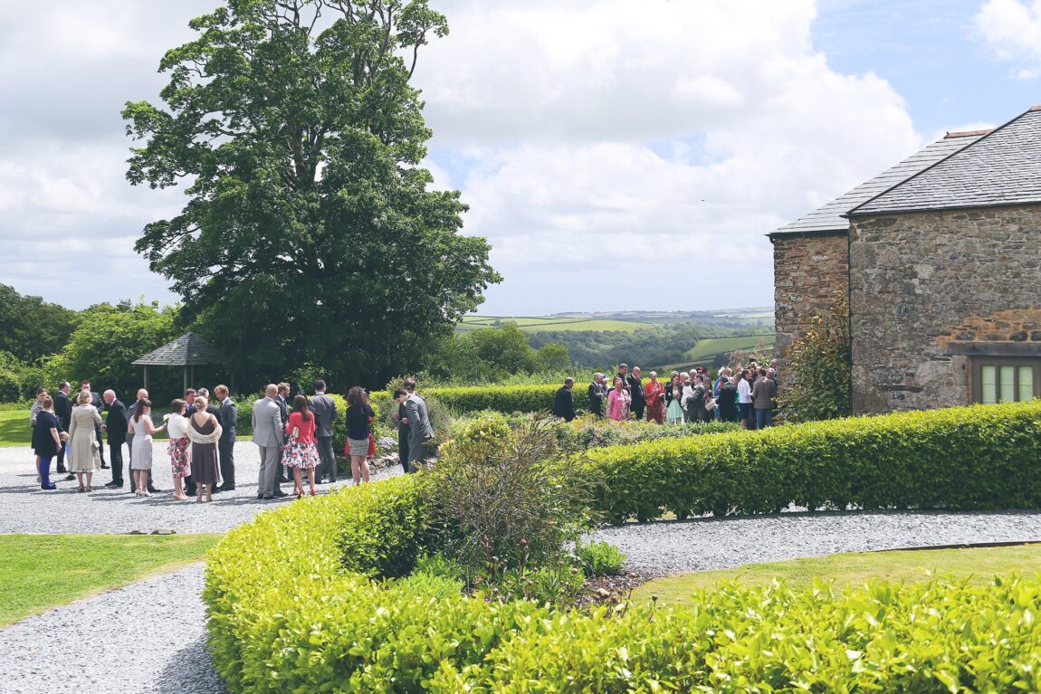 Wedding guests in the gardens at Trevenna with views over the Cornish countryside