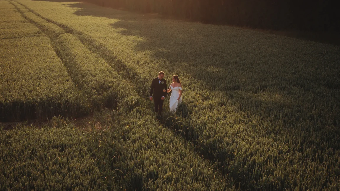 documentary wedding photography — drone view of couple walking through a wheat field at golden hour