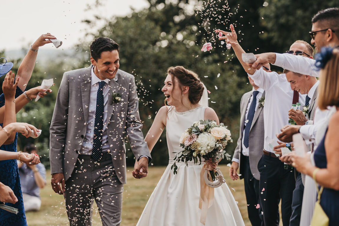 Nicola and Luke walking through confetti on the lawn at Hoath House